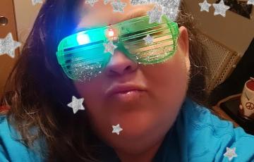 youngish native american woman wearing green sparkly glasses and a blue shirts with stars and a LTN balloon