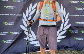 Athletic blood cancer survivor standing with finisher and baseball cap