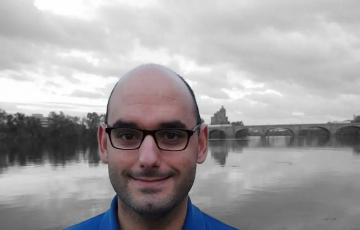 Acute myeloid leukemia survivor wearing a blue buttoned shirt in front of a beautiful landscape