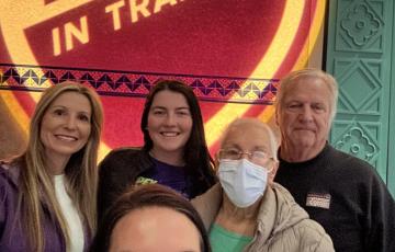 Alexis family of five with grandmother wearing glasses and a mask standing in front of TNT photo