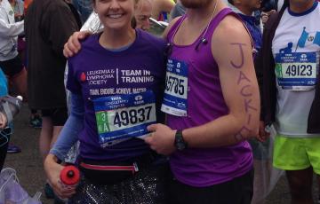 young white woman in a TNT shirt and race number and a sequined skirt with survivor written on her leg standing next to young white man with a black Nike hat beard and mustache
