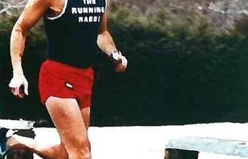 Hirshel middle aged white man balding with black glasses and mustache running in a black tank and red short the running rabbi