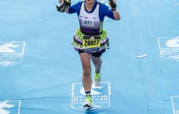 Teammate running across the Boston Marathon finish line to achieve the world majors and team in training jersey