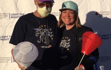 father with AML and daughter standing outside with light the night with hat team in training logos and red and white lanterns