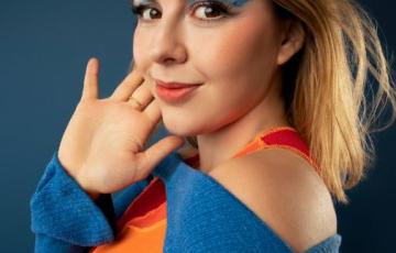 young adult leukemia survivor with vivid makeup and colorful clothes with closed mouth smile