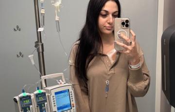 young adult patient lymphoma standing with IV pole in front of a mirror selfie
